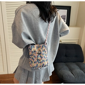Detail of floral drawstring crossbody bag with delicate patterns and adjustable strap