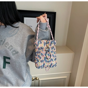 Floral crossbody bag with drawstrings and metal buckle shown in a lifestyle setting