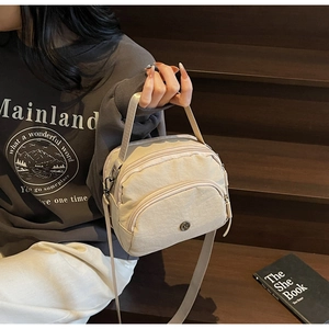 Detail of beige nylon shoulder bag with multi-zipper pockets and adjustable strap