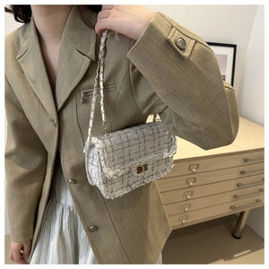 Detail of tweed crossbody bag with gold chain strap and metal lock shown on model