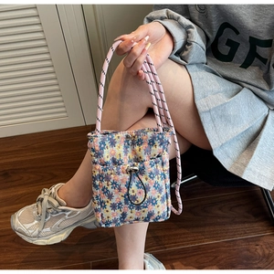 Detail of floral crossbody phone bag featuring a drawstring closure and woven strap