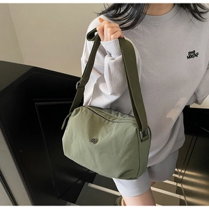 Detail of army green nylon crossbody bag with wide strap and metallic circular logo