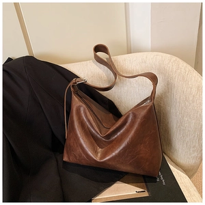 Close-up of vintage brown leather Hobo bag on a soft white boucle chair in a stylish setting