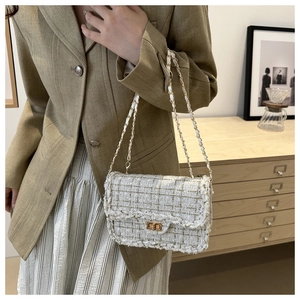 Detail of tweed crossbody bag featuring gold chain strap and textured fringe finish