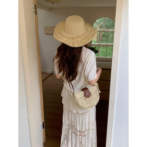 Minimalist straw woven half-moon shoulder bag and wide brim hat for a summer holiday look