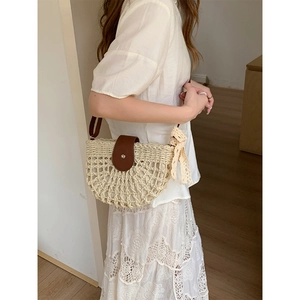 Handmade half-moon straw shoulder bag with brown leather trim and decorative lace scarf