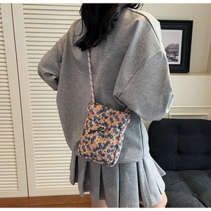 Detail of floral printed fabric crossbody phone bag with braided rope strap on a model