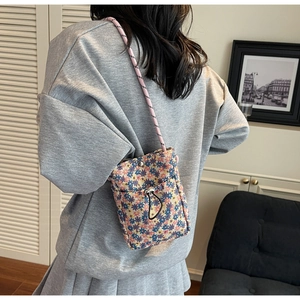 Detail of floral canvas crossbody phone bag with drawstring and woven shoulder strap