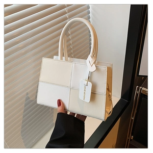 Détail du sac à main bicolore minimaliste en similicuir crème et blanc avec finitions