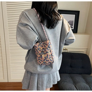 Floral crossbody phone bag with pink woven strap shown on model in modern interior