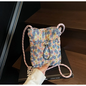 Close-up of a colorful woven crossbody phone bag with drawstring pocket and rope strap