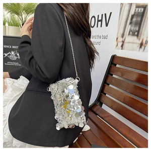 Close-up of a silver sequin crossbody bag with chain strap styled with a casual outfit