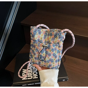 Detailed view of floral canvas phone bag with woven pink strap and drawstring pocket