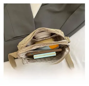 Detail showing spacious beige nylon crossbody bag interior with multiple compartments