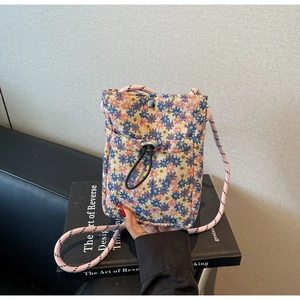 Macro detail of floral jacquard texture on crossbody bag with drawstring pocket