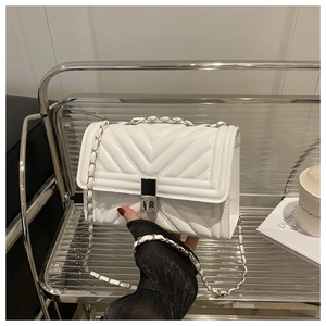 Détail d'un sac bandoulière blanc matelassé avec fermoir argenté et bandoulière en chaîne