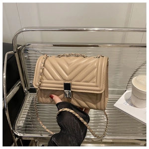Détail du sac matelassé beige avec fermoir argenté et bandoulière en chaîne métal