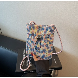Detailed close-up of woven floral fabric phone bag with adjustable drawstring and snap