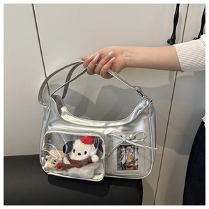 Détail d'un sac argenté métallisé avec fenêtre transparente montrant une peluche