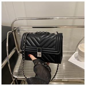 Détail du sac en similicuir noir surpiqué en V avec chaîne argentée et fermoir pivotant