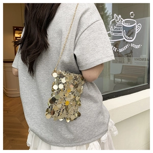 Close-up of a women's gold sequin mini tote bag with elegant chain strap outdoors