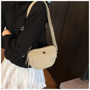 Beige nylon crossbody dumpling bag with adjustable wide strap shown on a model