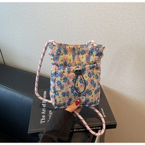 Detail of floral woven crossbody bag with drawstring closure and metal snap button