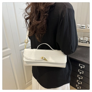 Detail of white crocodile pattern shoulder bag featuring a gold knot twist lock closure