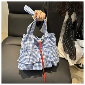 Gros plan du sac cabas à carreaux bleus avec volants superposés et cordon rouge et cordon de serrage