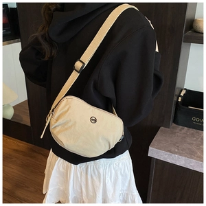 Detail of light beige crescent nylon crossbody bag with adjustable strap and metal emblem