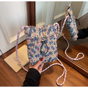 Detail of floral woven crossbody phone bag showing drawstrings and metal snap closure