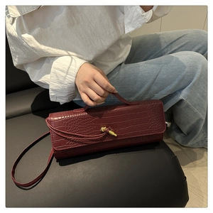 Fashionable crocodile pattern crossbody bag in dark red with a golden knot clasp detail