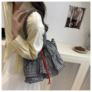 Détail du sac cabas à carreaux avec volants superposés et accents de cordon rouge
