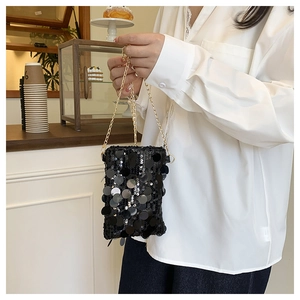 Detail of a chic black sequin mini crossbody bag with a gold chain strap held by a model