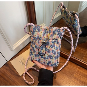 Detail of floral tapestry crossbody bag showing drawstring closure and pink rope strap