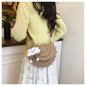 Detail of woven straw saddle bag with scalloped edges and cute cloud charm pendant