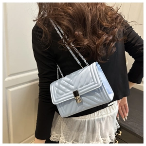 Gros plan du sac en cuir bleu clair à matelassage en V avec chaîne porté par un modèle