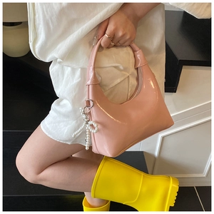 Detailed close-up of pink patent leather hobo bag with pearl bow charm ornament