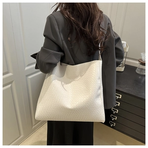 Détail du sac cabas blanc à texture tissée porté par un mannequin en intérieur épuré