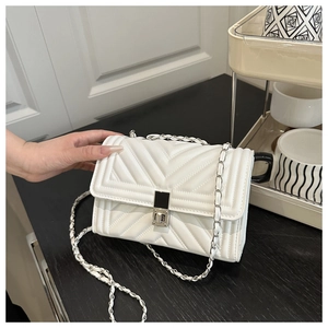 Détail du sac à bandoulière matelassé blanc avec chaîne argentée et fermoir en métal
