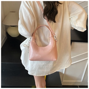 Detail of light pink half-moon bag with glossy finish and pearl bow charm accessory