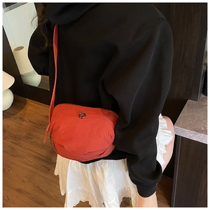 Rear view of a red nylon crescent crossbody bag with adjustable strap on a model