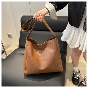 Détail d'un sac cabas marron à texture tressée avec style minimaliste et large poignée