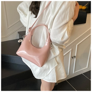 Close-up of pink glossy patent leather crescent bag with silver hardware and pearl charm