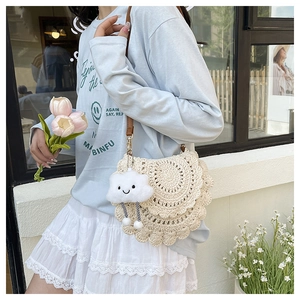 Detail of hand-woven cream saddle bag with wavy edges and cute cloud plush charm