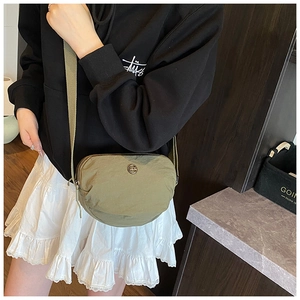 Olive green nylon crescent shoulder bag shown on model with street style outfit