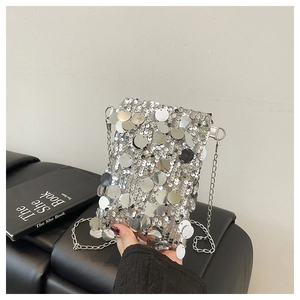Macro shot of silver sequin bag texture with thin metallic chain strap detail