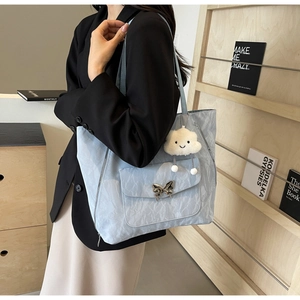 Close-up of light blue pleated tote bag featuring a silver butterfly buckle and cloud charm