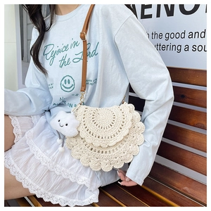 Close-up of beige crochet woven saddle bag with scalloped edges and cute cloud charm