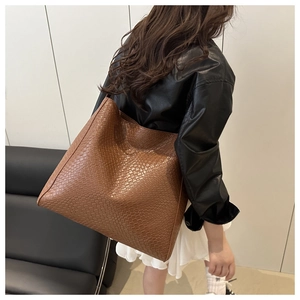 Détails de la texture tissée marron foncé sur un grand sac porté épaule minimaliste